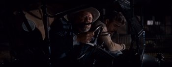 Movie still from “East of Eden” (1955), directed by Elia Kazan – A man in a hat and a suit driving a car; Medium shot, Over the shoulder angle