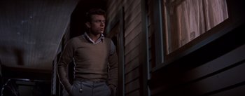Movie still from “East of Eden” (1955), directed by Elia Kazan – A man standing in front of a window wearing a sweater; Medium shot, Low angle