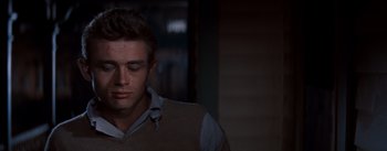 Movie still from “East of Eden” (1955), directed by Elia Kazan – A young man in a brown sweater looking down at his face; Close Up shot, Over the shoulder angle