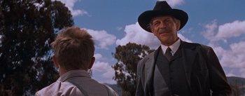 Movie still from “East of Eden” (1955), directed by Elia Kazan – A man in a hat and a suit talking to a young boy; Medium shot, Low angle