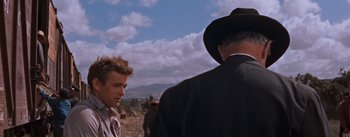 Movie still from “East of Eden” (1955), directed by Elia Kazan – A man in a suit and a hat standing next to another man in a hat; Medium shot, Over the shoulder angle