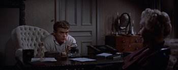 Movie still from “East of Eden” (1955), directed by Elia Kazan – A man sitting at a table in front of a bottle of whiskey; Medium shot, Over the shoulder angle