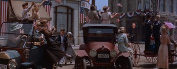Movie still from “East of Eden” (1955), directed by Elia Kazan – An old red car is driving down the street; Wide shot, Low angle