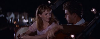 Movie still from “East of Eden” (1955), directed by Elia Kazan – A woman in a pink dress holding a cello; Close Up shot, Over the shoulder angle