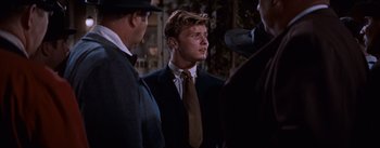 Movie still from “East of Eden” (1955), directed by Elia Kazan – A man in a suit and tie standing in front of two other men; Medium shot, Over the shoulder angle