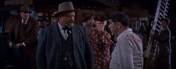 Movie still from “East of Eden” (1955), directed by Elia Kazan – A man in a suit and hat talking to another man in a hat; Medium shot, Over the shoulder angle