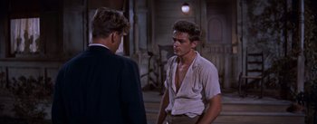 Movie still from “East of Eden” (1955), directed by Elia Kazan – A man wearing a white shirt is talking to another man in a black suit; Medium shot, Over the shoulder angle