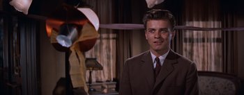 Movie still from “East of Eden” (1955), directed by Elia Kazan – A man wearing a suit and tie standing next to an umbrella; Close Up shot, Over the shoulder angle