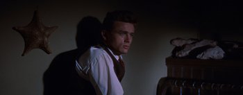 Movie still from “East of Eden” (1955), directed by Elia Kazan – A man wearing a neck tie standing in a dark room; Medium shot, Low angle
