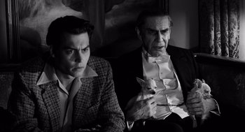 Movie still from “Ed Wood” (1994), directed by Tim Burton – A man holding a cat next to another man in a suit; Medium shot, Over the shoulder angle
