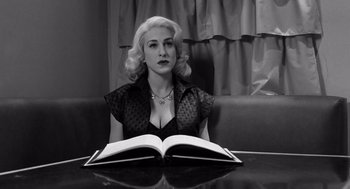 Movie still from “Ed Wood” (1994), directed by Tim Burton – A woman sitting in front of an open book on top of a table; Close Up shot, High angle