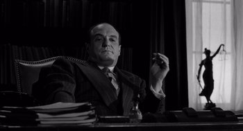 Movie still from “Ed Wood” (1994), directed by Tim Burton – A man sitting at a desk in front of a stack of papers; Medium shot, Low angle