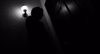 Movie still from “Ed Wood” (1994), directed by Tim Burton – A man standing in front of a door in a dark room; Medium shot, Low angle