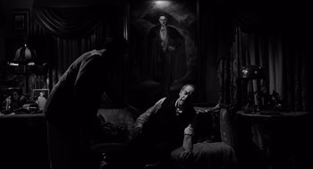 Movie still from “Ed Wood” (1994), directed by Tim Burton – A man sitting on a couch in front of a painting; Medium shot, Low angle
