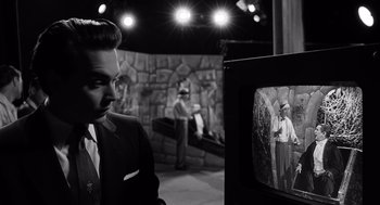 Movie still from “Ed Wood” (1994), directed by Tim Burton – A black and white photo of a man in a suit and tie looking at a television screen; Medium shot, Over the shoulder angle