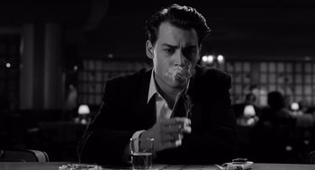Movie still from “Ed Wood” (1994), directed by Tim Burton – A man sitting at a table with a cigarette in his mouth; Close Up shot, Low angle