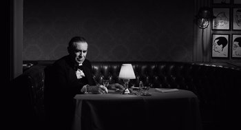 Movie still from “Ed Wood” (1994), directed by Tim Burton – A man sitting at a table with a glass in front of him; Medium shot, Low angle