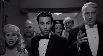 Movie still from “Ed Wood” (1994), directed by Tim Burton – A man in a tuxedo surrounded by other people; Medium shot, Low angle