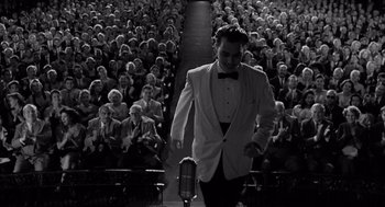 Movie still from “Ed Wood” (1994), directed by Tim Burton – A black and white photo of a man in a suit and bow tie in front of an audience; Wide shot, Low angle