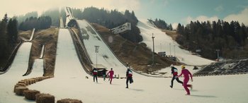 Movie still from “Eddie the Eagle” (2015), directed by Dexter Fletcher – A group of skiers on a snowy slope; Extreme Wide shot, High angle