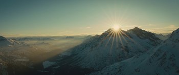 Movie still from “Eddie the Eagle” (2015), directed by Dexter Fletcher – The sun is setting over a snowy mountain; Extreme Wide shot, Low angle