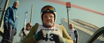 Movie still from “Eddie the Eagle” (2015), directed by Dexter Fletcher – An older woman wearing goggles and a ski helmet; Close Up shot, Low angle