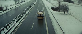 Movie still from “Eddie the Eagle” (2015), directed by Dexter Fletcher – A bus driving down a road in the snow; Extreme Wide shot, High angle