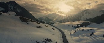 Movie still from “Eddie the Eagle” (2015), directed by Dexter Fletcher – The sun is setting over a snowy mountain; Extreme Wide shot, High angle