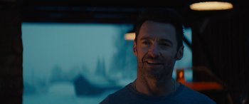 Movie still from “Eddie the Eagle” (2015), directed by Dexter Fletcher – A person wearing headphones and smiling; Close Up shot, Over the shoulder angle