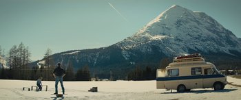 Movie still from “Eddie the Eagle” (2015), directed by Dexter Fletcher – A boat is parked in the middle of a snow covered field; Extreme Wide shot, Low angle