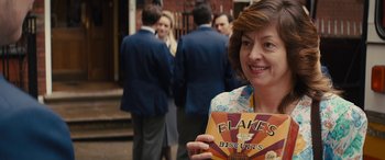 Movie still from “Eddie the Eagle” (2015), directed by Dexter Fletcher – A woman standing in front of a group of people; Close Up shot, Over the shoulder angle