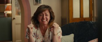 Movie still from “Eddie the Eagle” (2015), directed by Dexter Fletcher – A woman with her hands in the air and her mouth open; Close Up shot, High angle
