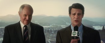 Movie still from “Eddie the Eagle” (2015), directed by Dexter Fletcher – Two men in suits are standing next to each other; Medium shot, Low angle