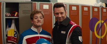 Movie still from “Eddie the Eagle” (2015), directed by Dexter Fletcher – Two men standing next to each other in front of lockers; Close Up shot, Over the shoulder angle