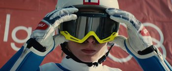 Movie still from “Eddie the Eagle” (2015), directed by Dexter Fletcher – A person wearing goggles and a helmet; Close Up shot, Low angle