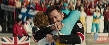 Movie still from “Eddie the Eagle” (2015), directed by Dexter Fletcher – Two men fighting in front of a crowd of onlookers; Medium shot, Over the shoulder angle