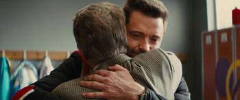 Movie still from “Eddie the Eagle” (2015), directed by Dexter Fletcher – Two men are hugging each other in a room; Close Up shot, Over the shoulder angle