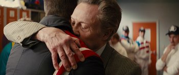 Movie still from “Eddie the Eagle” (2015), directed by Dexter Fletcher – An older man is hugging a younger man; Close Up shot, Over the shoulder angle