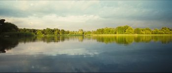 Movie still from “Eden Lake” (2008), directed by James Watkins – A body of water surrounded by trees and a cloudy sky; Extreme Wide shot, High angle