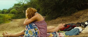 Movie still from “Eden Lake” (2008), directed by James Watkins – A man and a woman laying on a blanket on the beach; Wide shot, High angle
