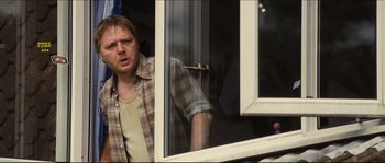 Movie still from “Eden Lake” (2008), directed by James Watkins – A man standing in front of a sliding glass door; Medium shot, Over the shoulder angle