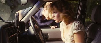 Movie still from “Eden Lake” (2008), directed by James Watkins – A woman sitting in the driver's seat of a car; Medium shot, Over the shoulder angle
