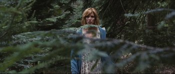 Movie still from “Eden Lake” (2008), directed by James Watkins – A woman standing in the middle of a forest; Medium shot, Low angle