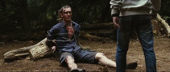 Movie still from “Eden Lake” (2008), directed by James Watkins – A man with a barbed wire around his neck; Medium shot, High angle