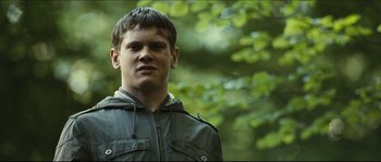 Movie still from “Eden Lake” (2008), directed by James Watkins – A young man in a green jacket stands in front of a tree; Close Up shot, Low angle