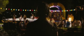 Movie still from “Eden Lake” (2008), directed by James Watkins – A man with long black hair standing in front of a crowd; Medium shot, Over the shoulder angle