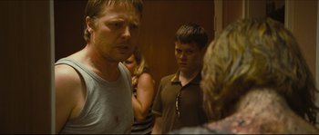 Movie still from “Eden Lake” (2008), directed by James Watkins – A group of people standing in a room talking to each other; Close Up shot, Over the shoulder angle