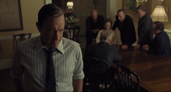 Movie still from “The Post” (2017), directed by Steven Spielberg – A group of people sitting in a room with a man in a striped dress shirt; Medium shot, Over the shoulder angle