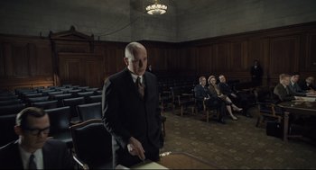 Movie still from “The Post” (2017), directed by Steven Spielberg – A man in a suit stands in front of a group of people; Wide shot, Low angle