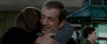 Movie still from “Edge of Darkness” (2010), directed by Martin Campbell – A man and a woman hugging each other in front of a building; Close Up shot, Over the shoulder angle